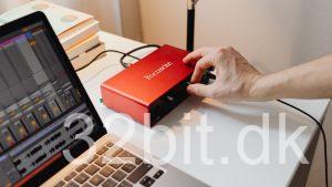 Rødt USB-lydkort tilsluttet en bærbar med et lydprogram åbent