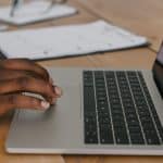 Hånd på touchpladen af en bærbar computer ved et skrivebord