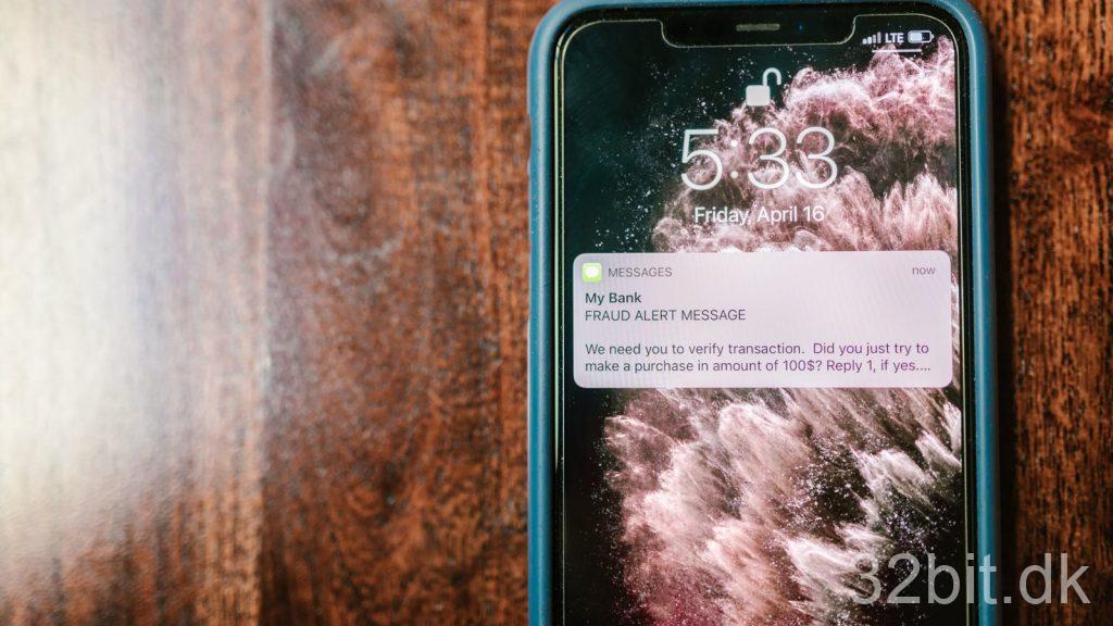 iPhone på et træbord med en falsk advarsel på låseskærmen