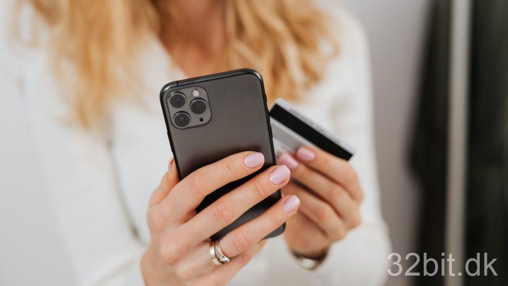 Kvinde med smartphone og betalingskort i hænderne under et onlinekøb