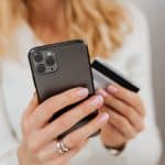 Kvinde med smartphone og betalingskort i hænderne under et onlinekøb