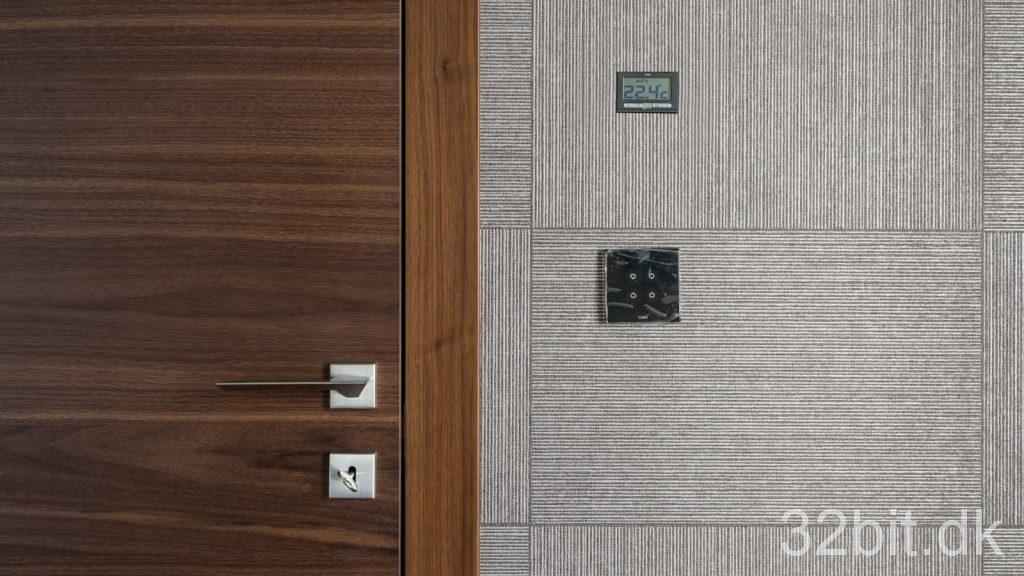 Smart home-betjeningspanel og kontakt på en væg ved en dør